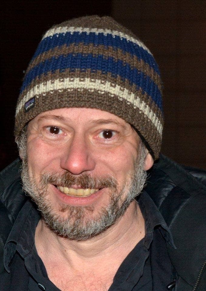 Mathieu Amalric in a striped woollen hat, smiling
