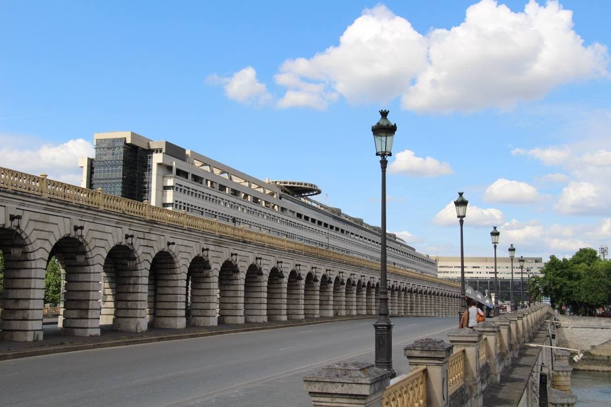 A long building on arches running out over the river beside a bridge