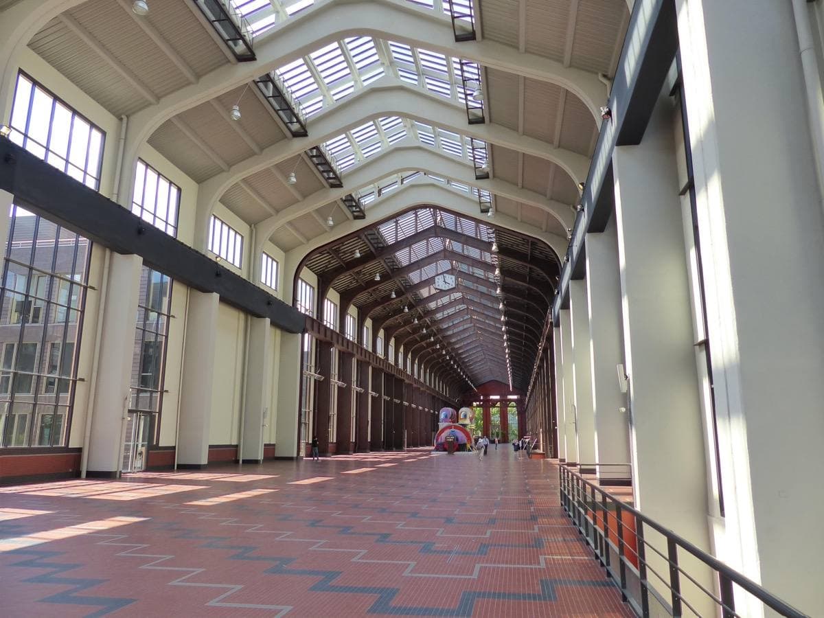 A long hall with a glass roof, white pillars and a red-tiled floor