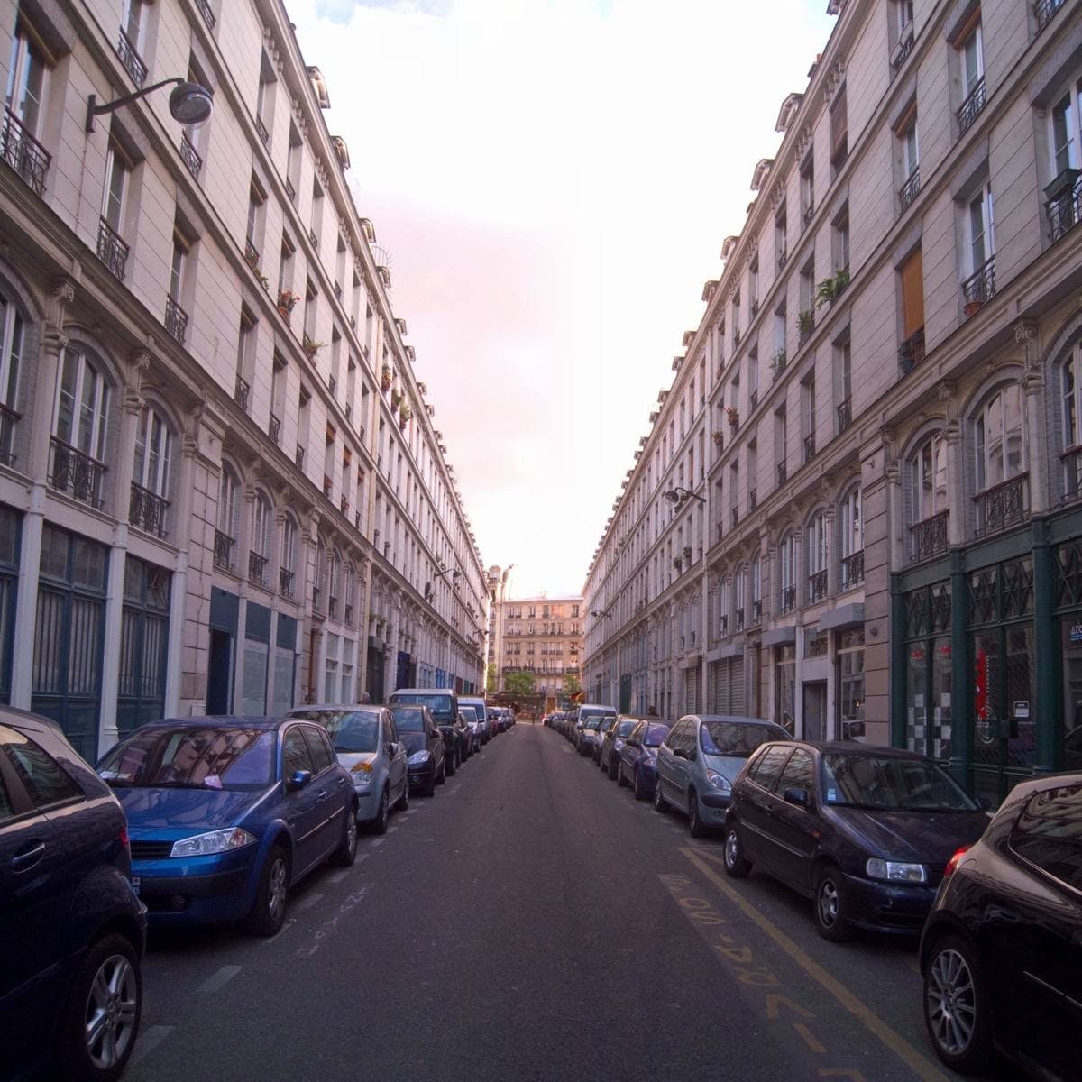 A straight street between two identical rows of iron and stone buildings