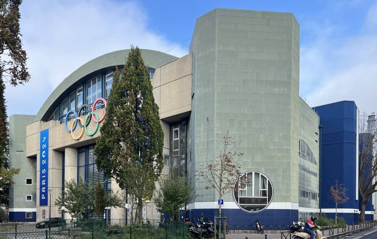 The pool building with Olympic rings and a tall concrete tower