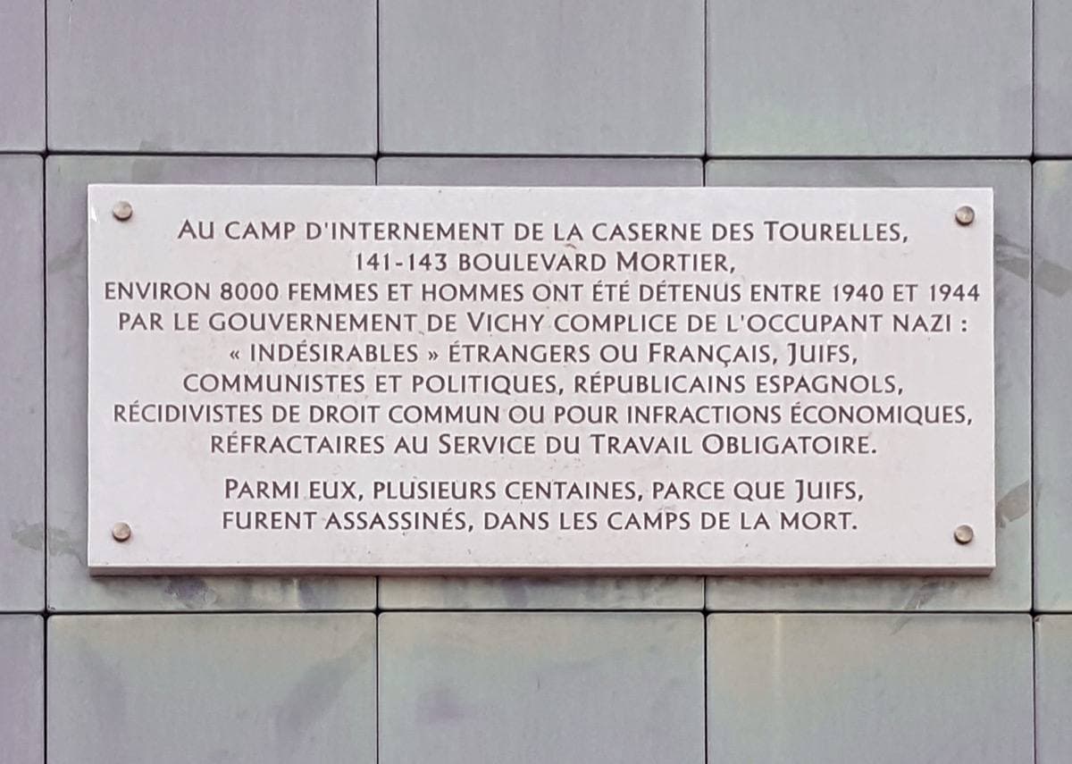 A stone plaque with a carved inscription set into a pale wall