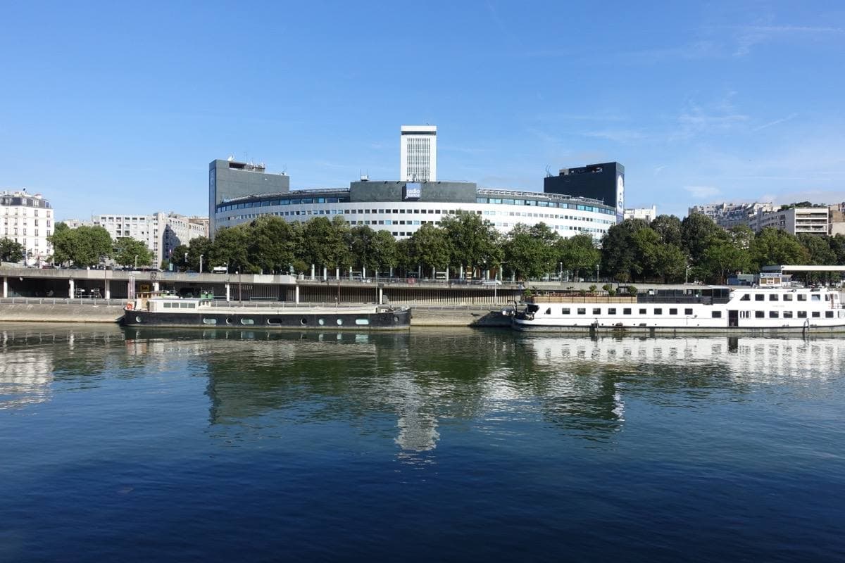 A round building with a tall tower, reflected in the river