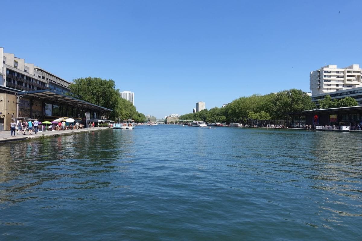 A wide stretch of canal water with trees and tall buildings on the far bank
