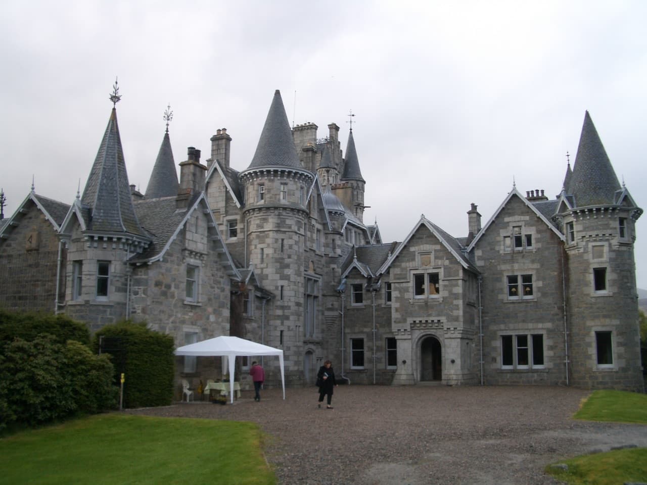 A grey granite Scottish baronial house with pointed turrets and a gravel forecourt