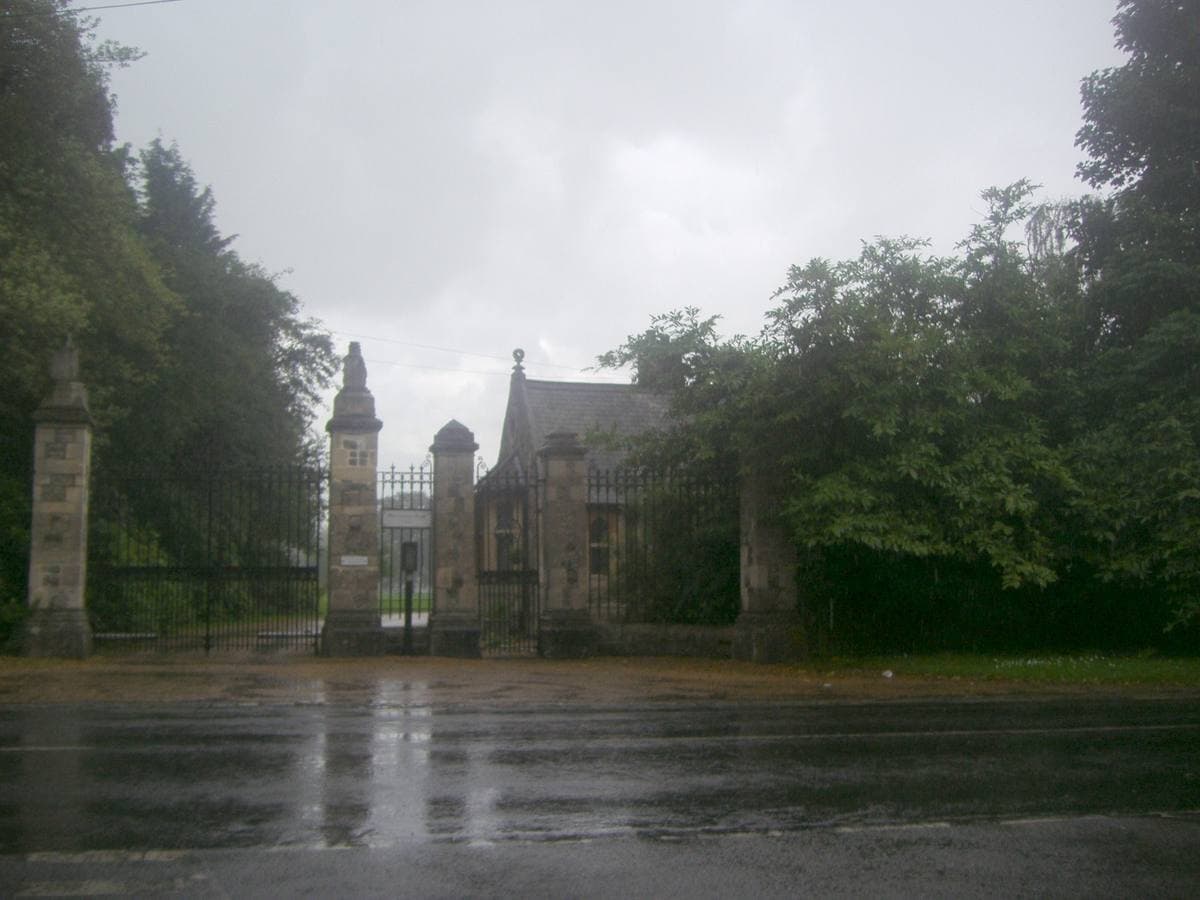 Gate piers and a lodge at the entrance to a private estate beside a country road