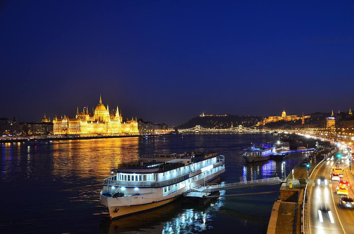The lit Gothic Revival Parliament building reflected in the Danube at night