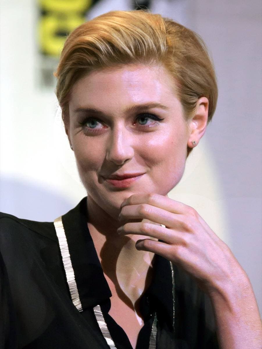 Elizabeth Debicki, blonde hair swept back, speaking at a microphone