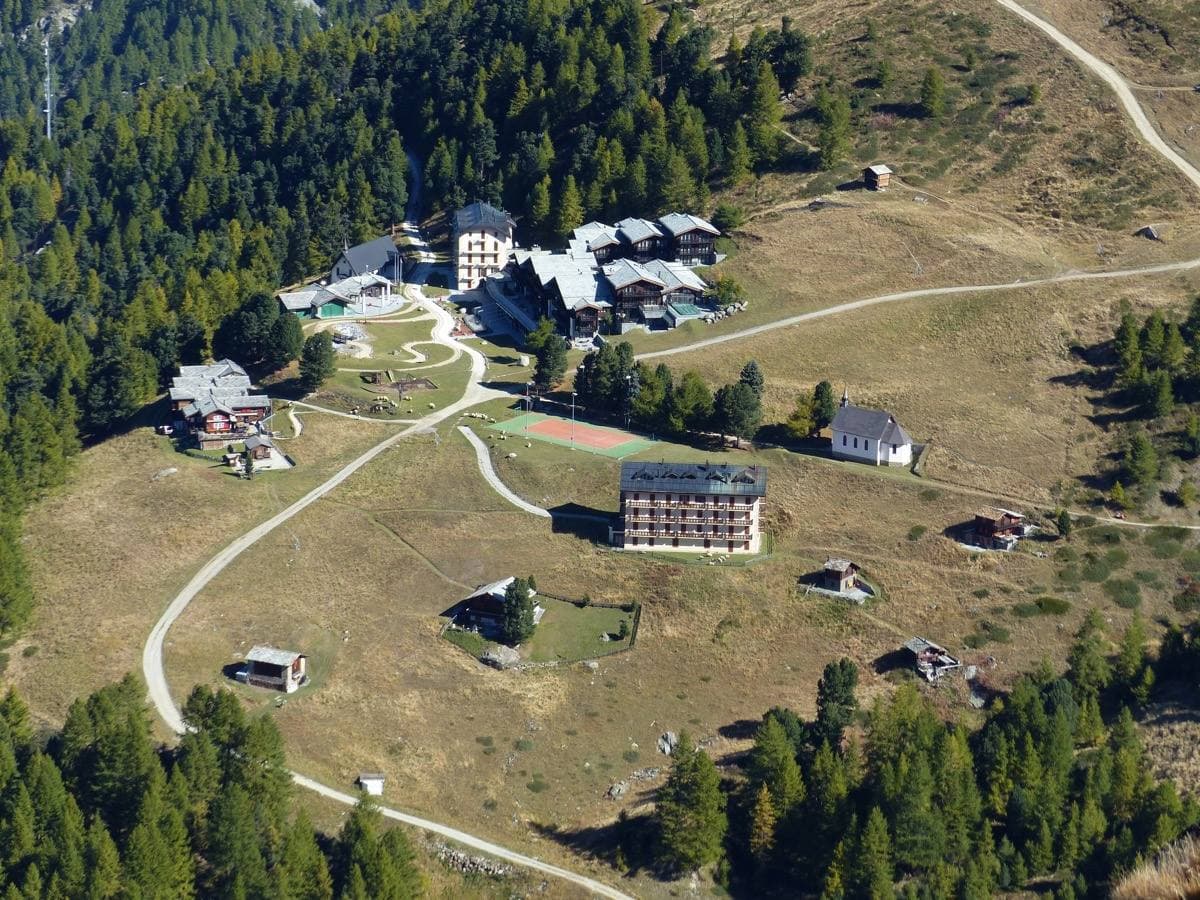 A large mountain hotel on an alpine shelf among larches