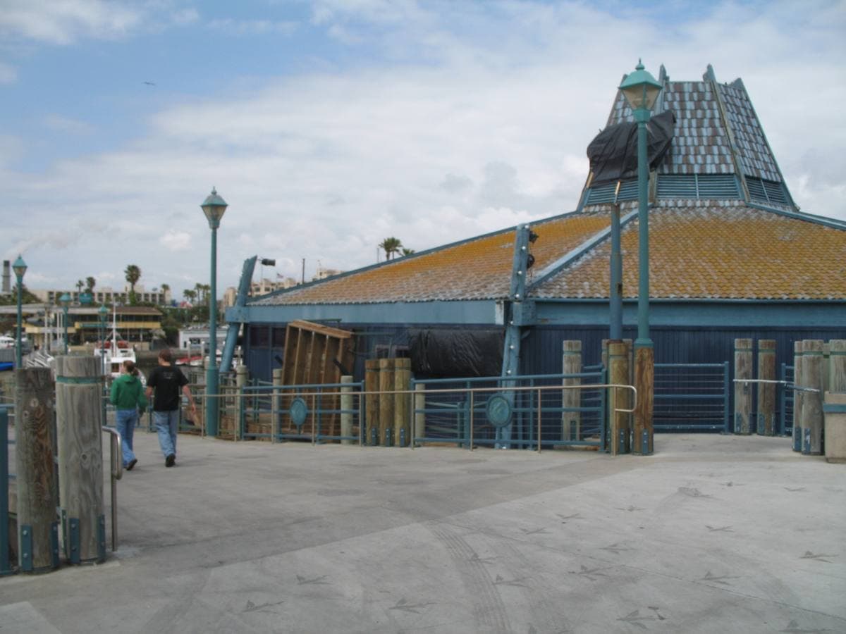 A blue-roofed octagonal building on a pier deck under a clear sky
