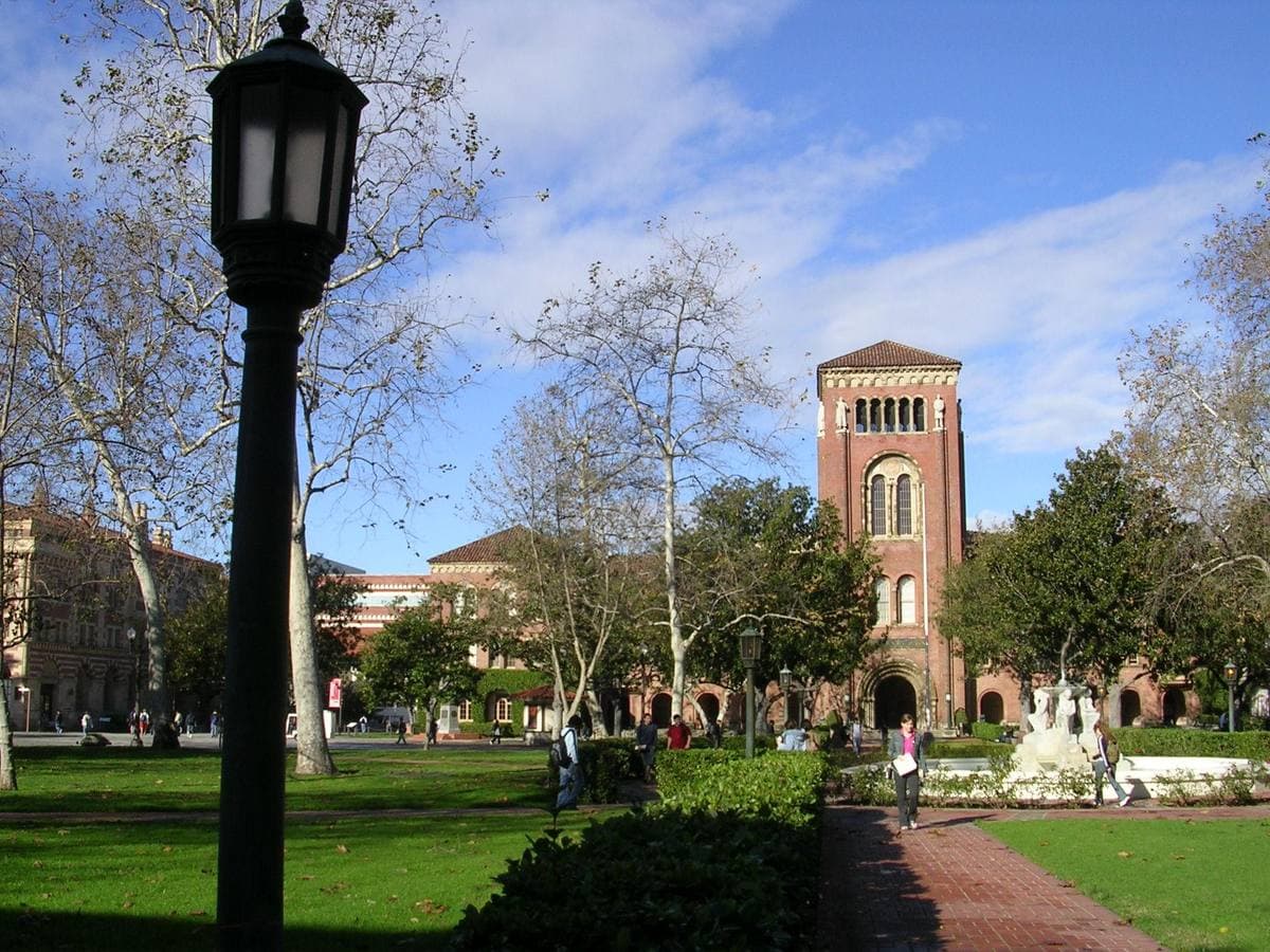 A red-brick Romanesque tower beyond lawns and trees