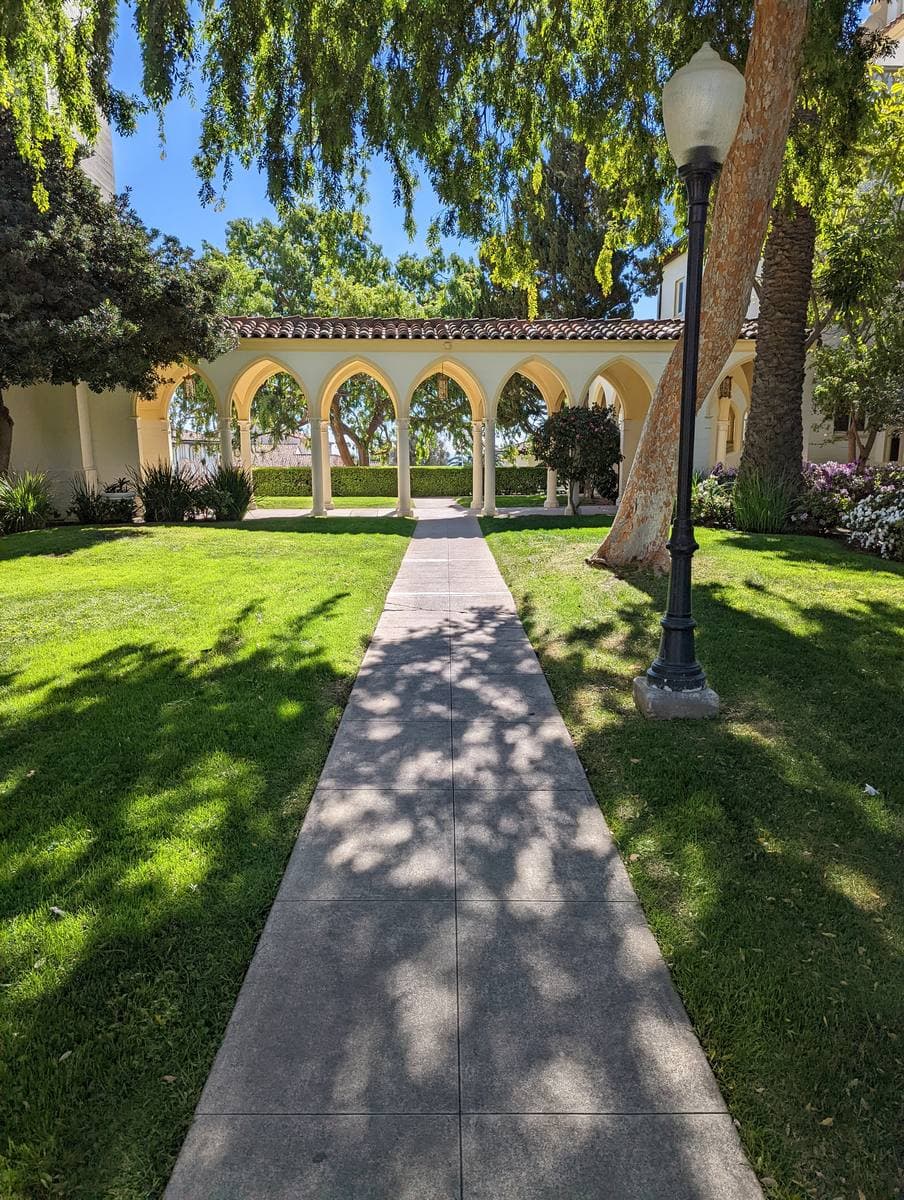A straight path across a lawn to an arcaded building