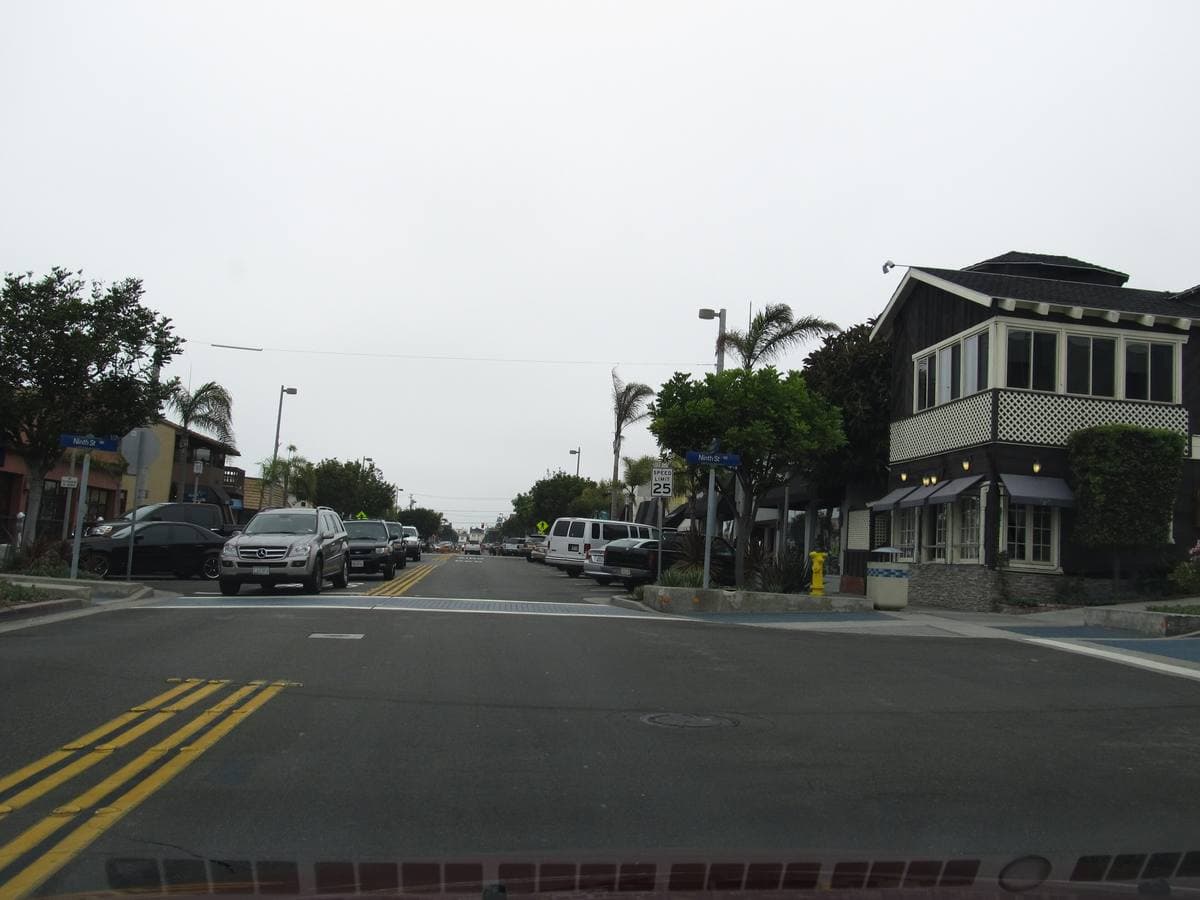 A quiet residential street with parked cars and low houses