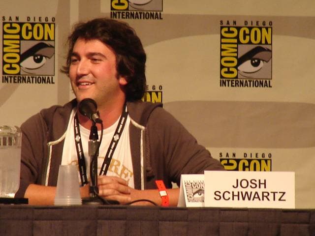 Josh Schwartz speaking at a panel table behind a name card