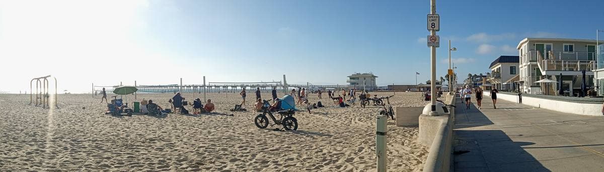 A wide beach beside a paved promenade under a blue sky