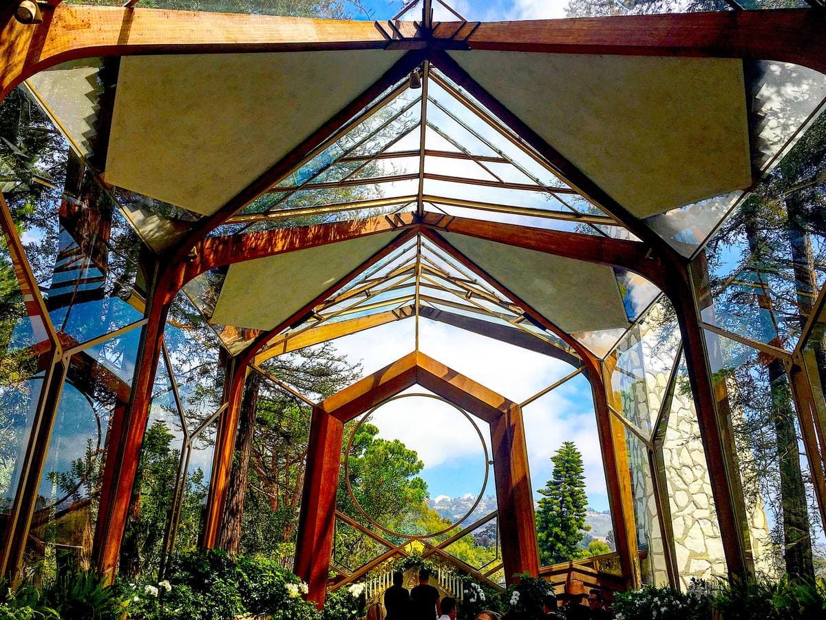 A glass and timber chapel with redwood trees seen through its roof