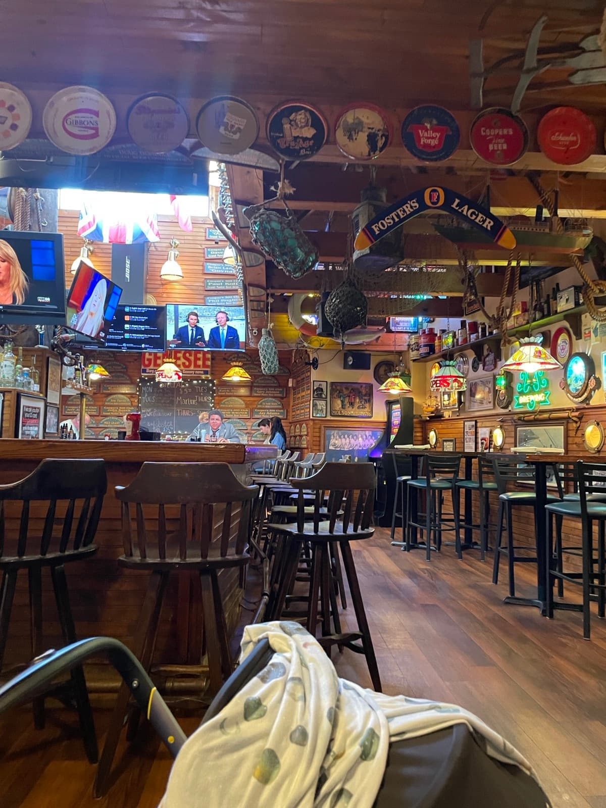A wood-panelled bar crowded with signs, trays and memorabilia over high stools