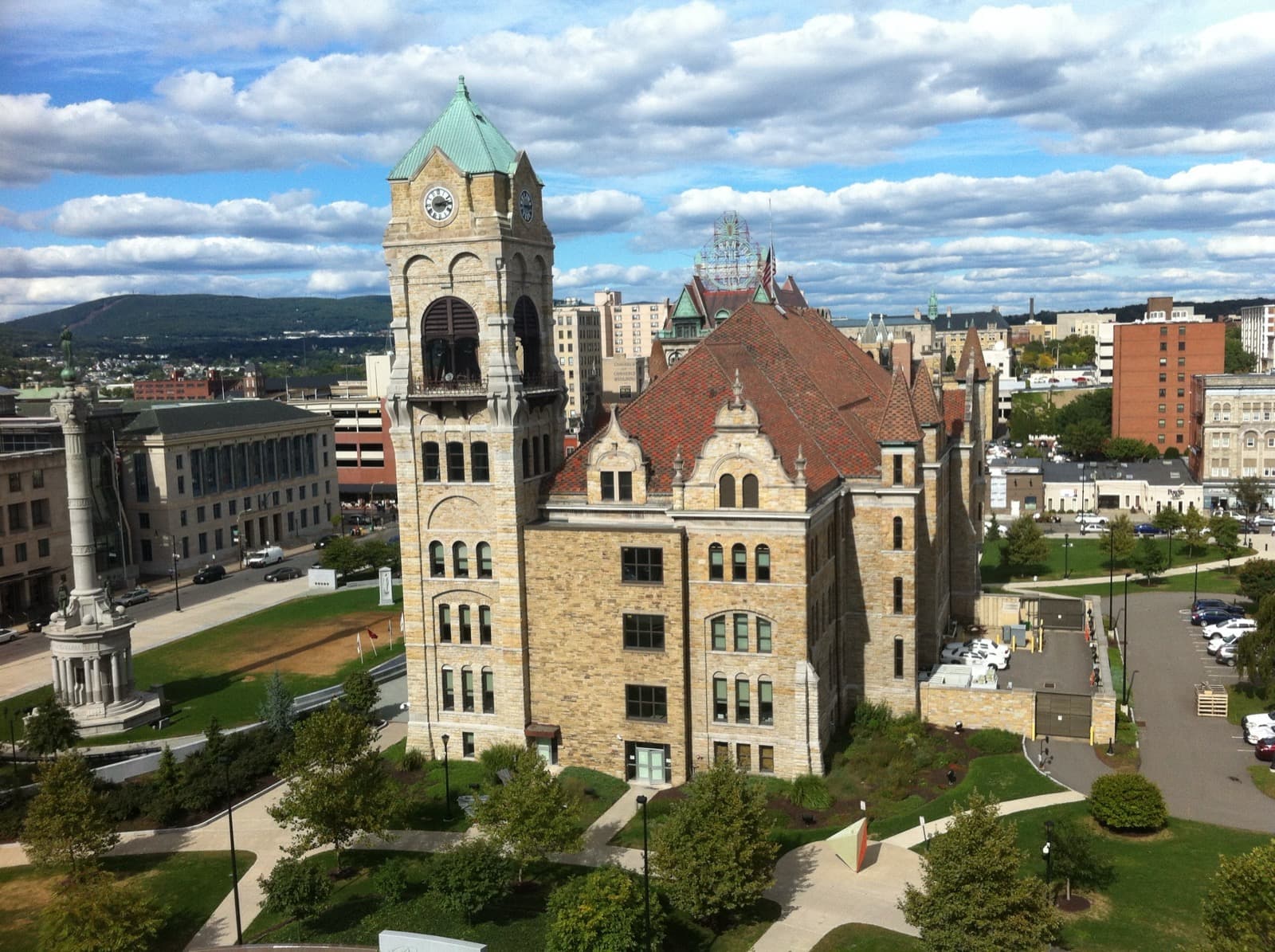 A stone courthouse with a green-capped clock tower in a square of lawns and paths