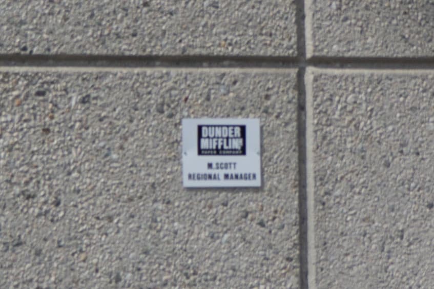 A tiny Dunder Mifflin sign reading M. Scott, Regional Manager, on rough concrete