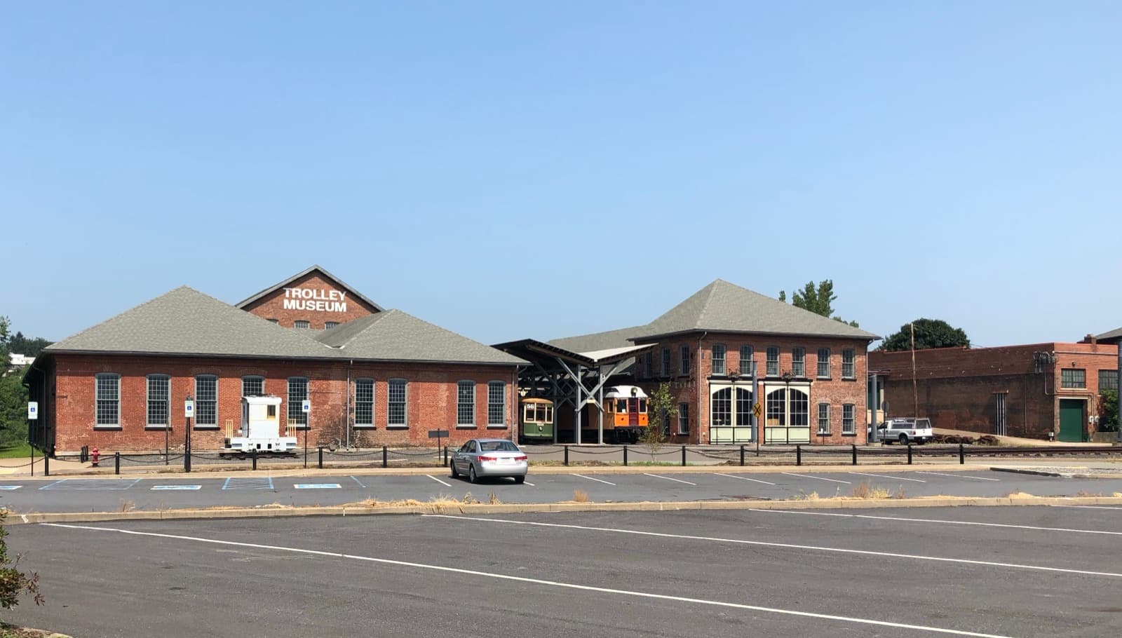 Low red-brick station buildings with hipped roofs beside a wide car park