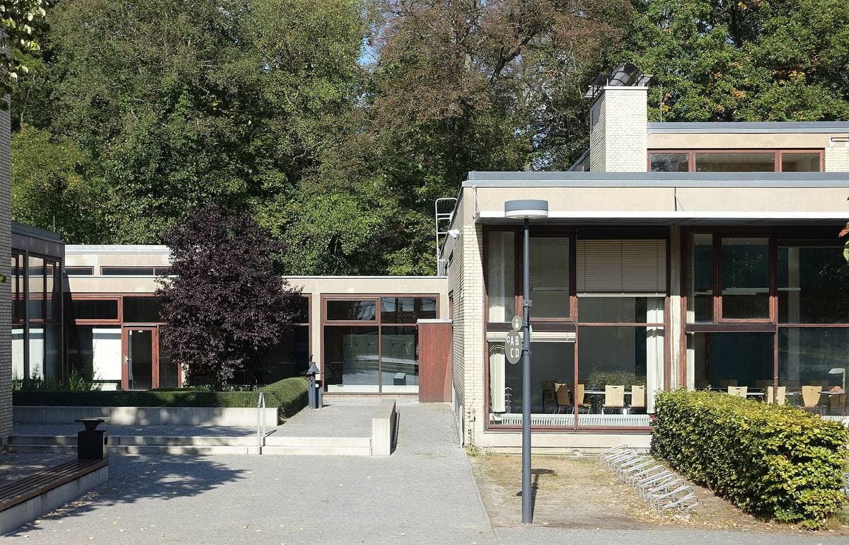 A brick and stucco institutional building behind trees