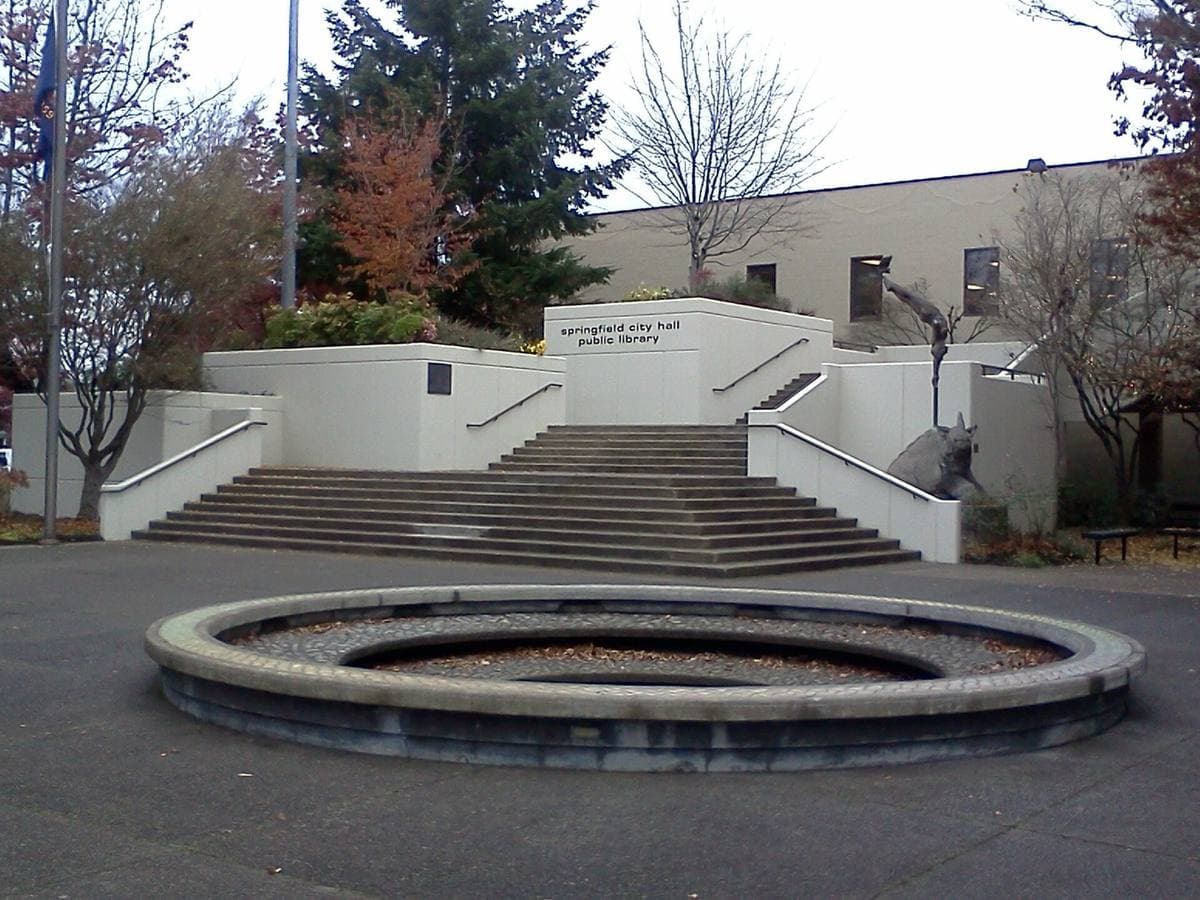 Wide concrete steps and a round planter in front of a low civic building