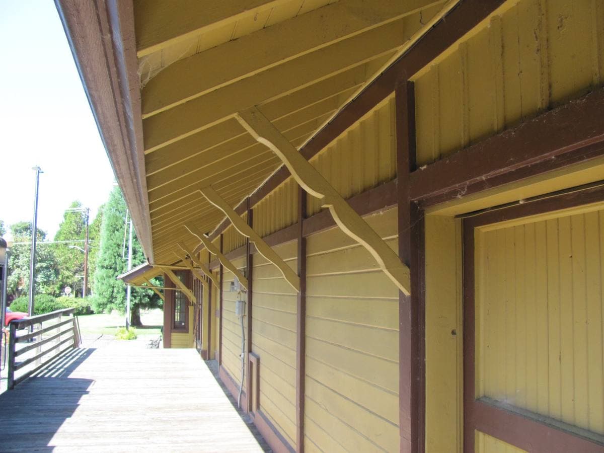 The yellow timber platform canopy of a small railroad depot