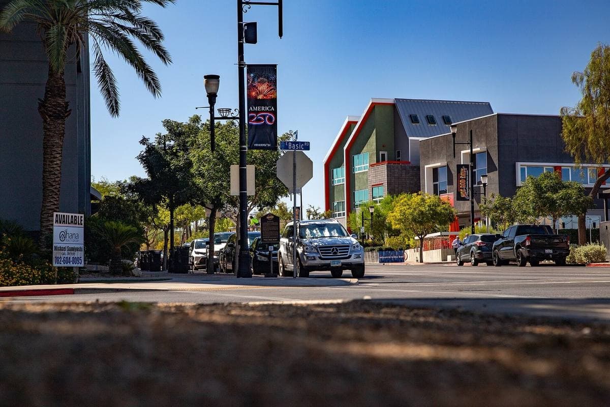A sunny desert-town street corner with palm trees and new buildings