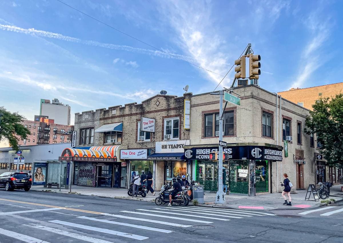 Corner shops under a traffic light on a sunny Astoria street