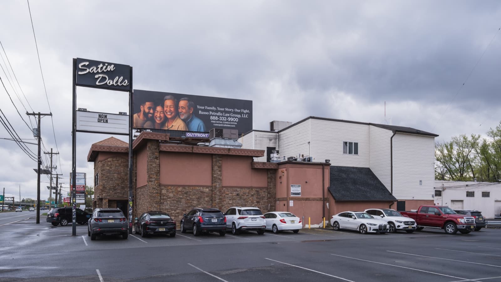 A low club building with a Satin Dolls sign and a car park in front