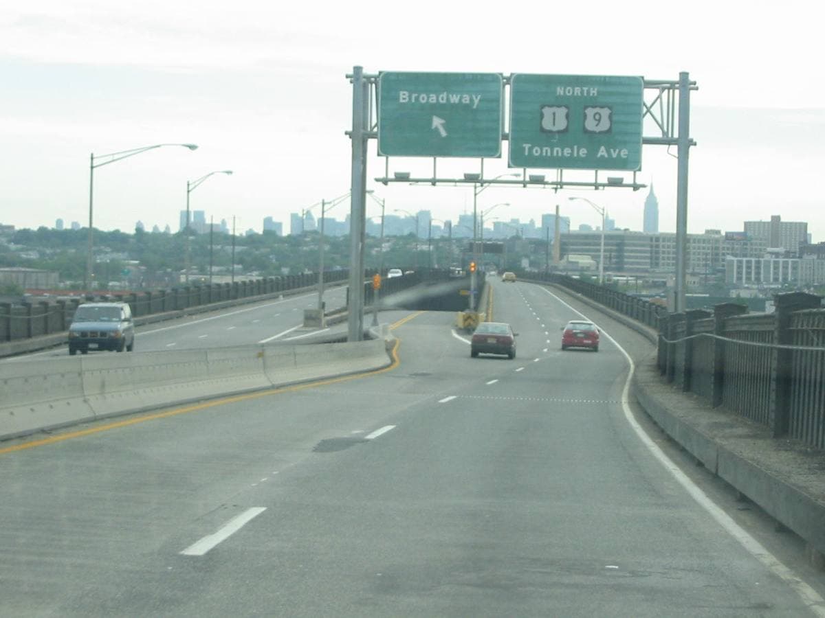 A highway on a viaduct with green exit signs for Broadway and Tonnele Avenue