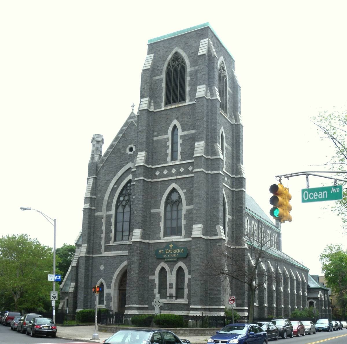 A tall grey Gothic church on a street corner with traffic lights