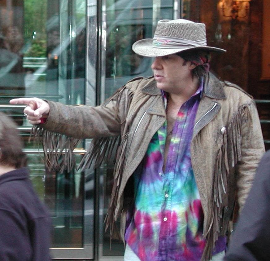 Steven Van Zandt in a cowboy hat and fringed jacket, pointing