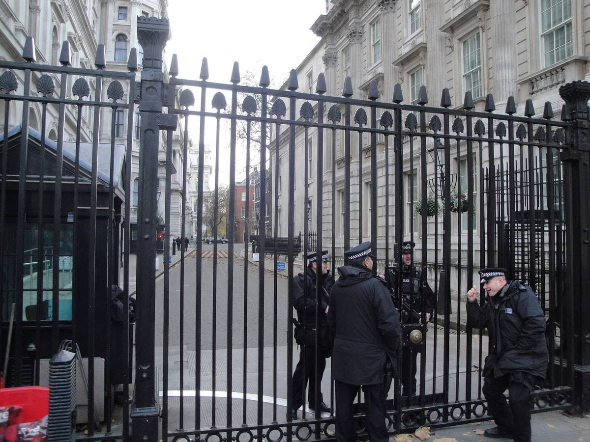 Black iron security gates across Downing Street with police officers behind them