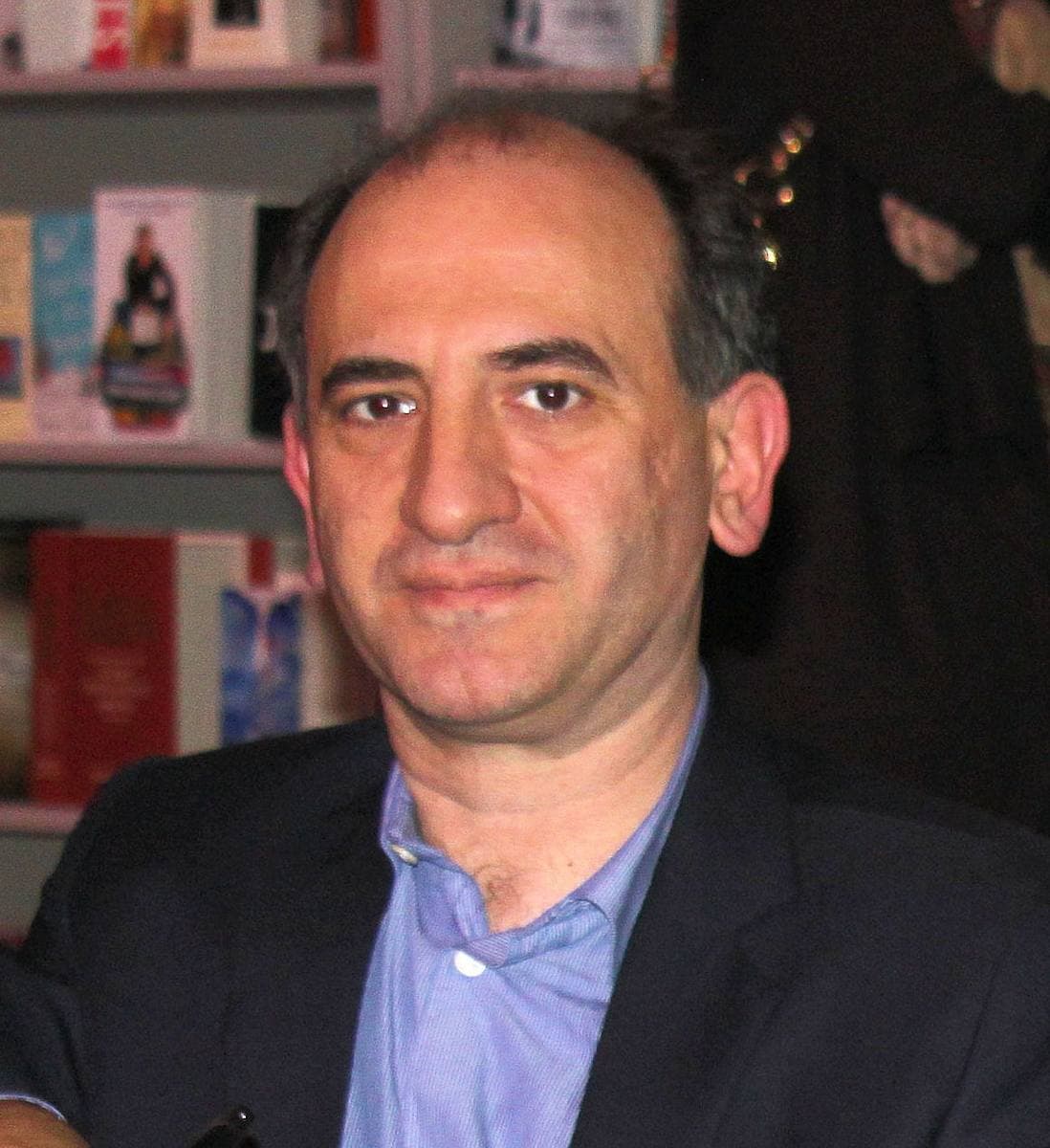Armando Iannucci in a dark jacket and blue shirt at a book signing