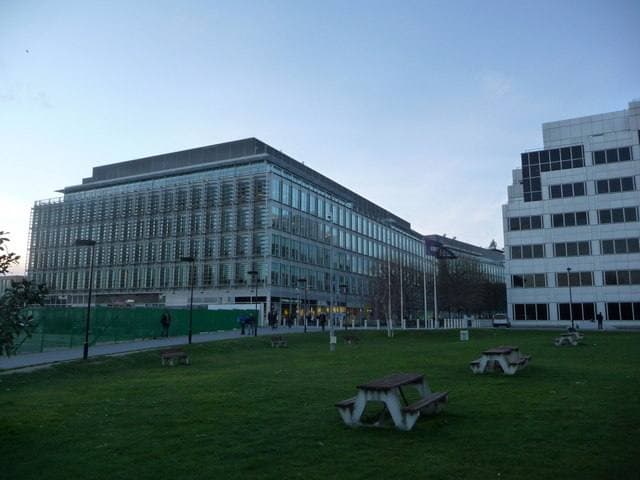 A glass office block beside a lawn with picnic tables