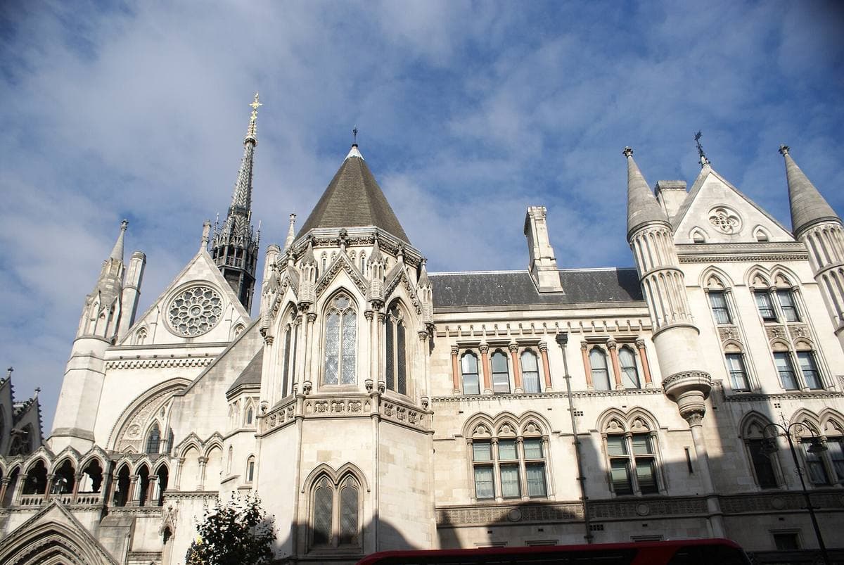 The pale Gothic spires and rose window of the Royal Courts of Justice against a blue sky