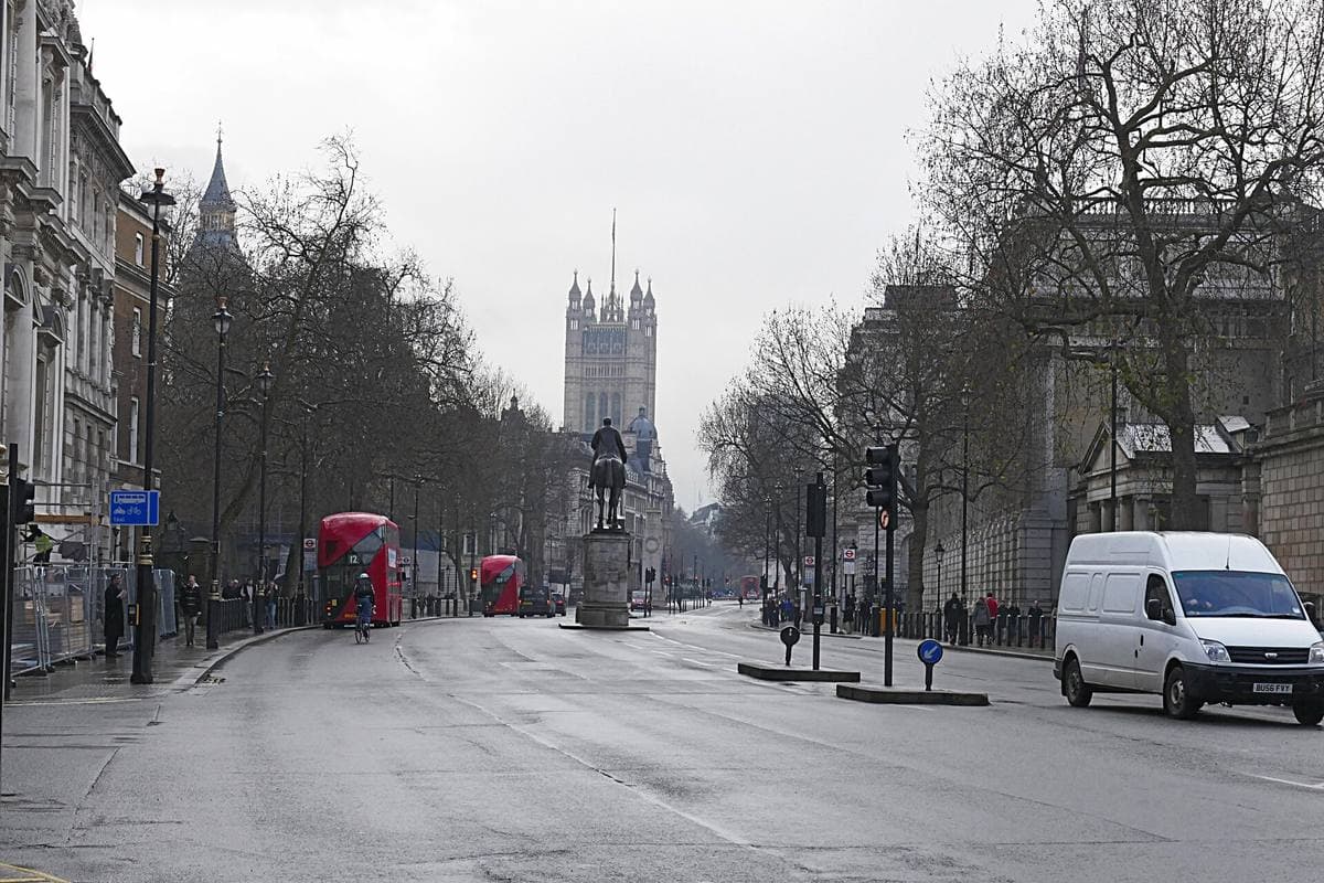 Whitehall, wide and nearly empty, with red buses and the Victoria Tower at the far end