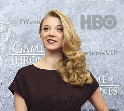 Natalie Dormer with long wavy fair hair, in a dark dress, at a premiere
