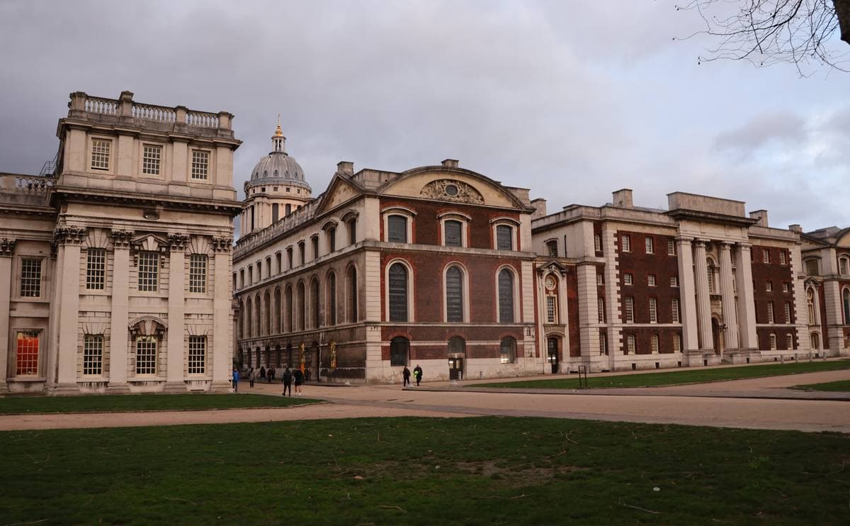 Two matching baroque colonnaded buildings with domes either side of a lawn
