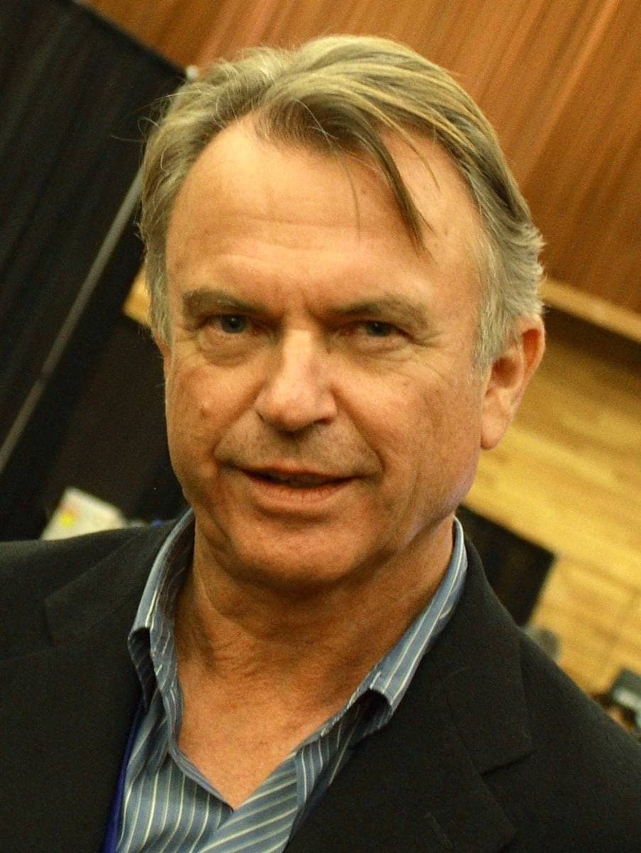 Sam Neill in a dark jacket and open-necked blue shirt