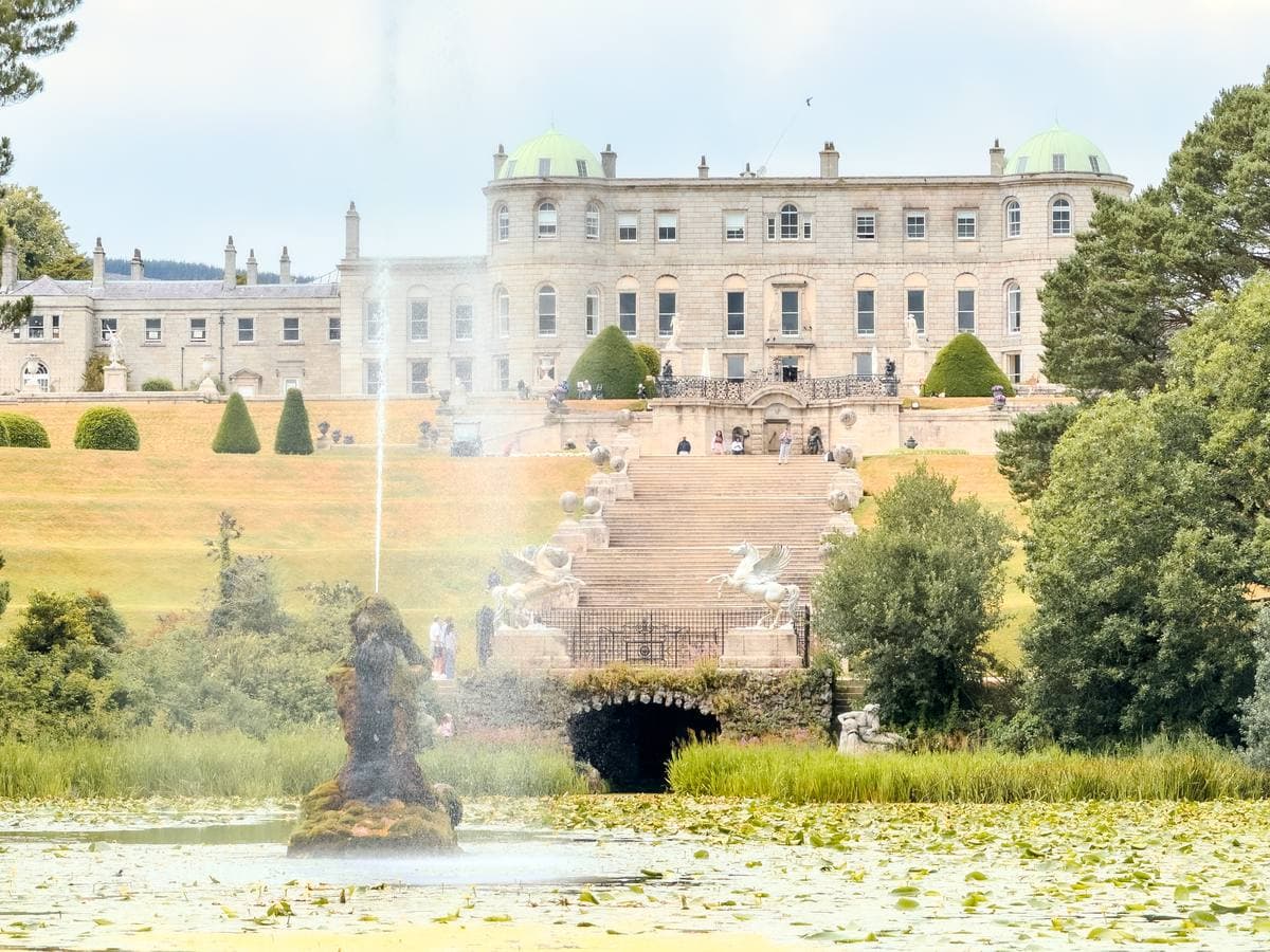 A long pale Palladian house above terraces, a fountain and a lake