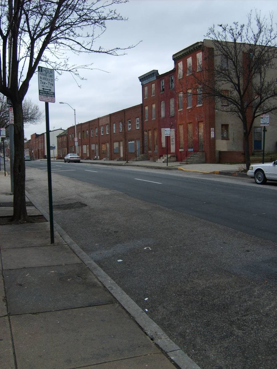 A row of brick rowhouses along an empty West Baltimore street in winter
