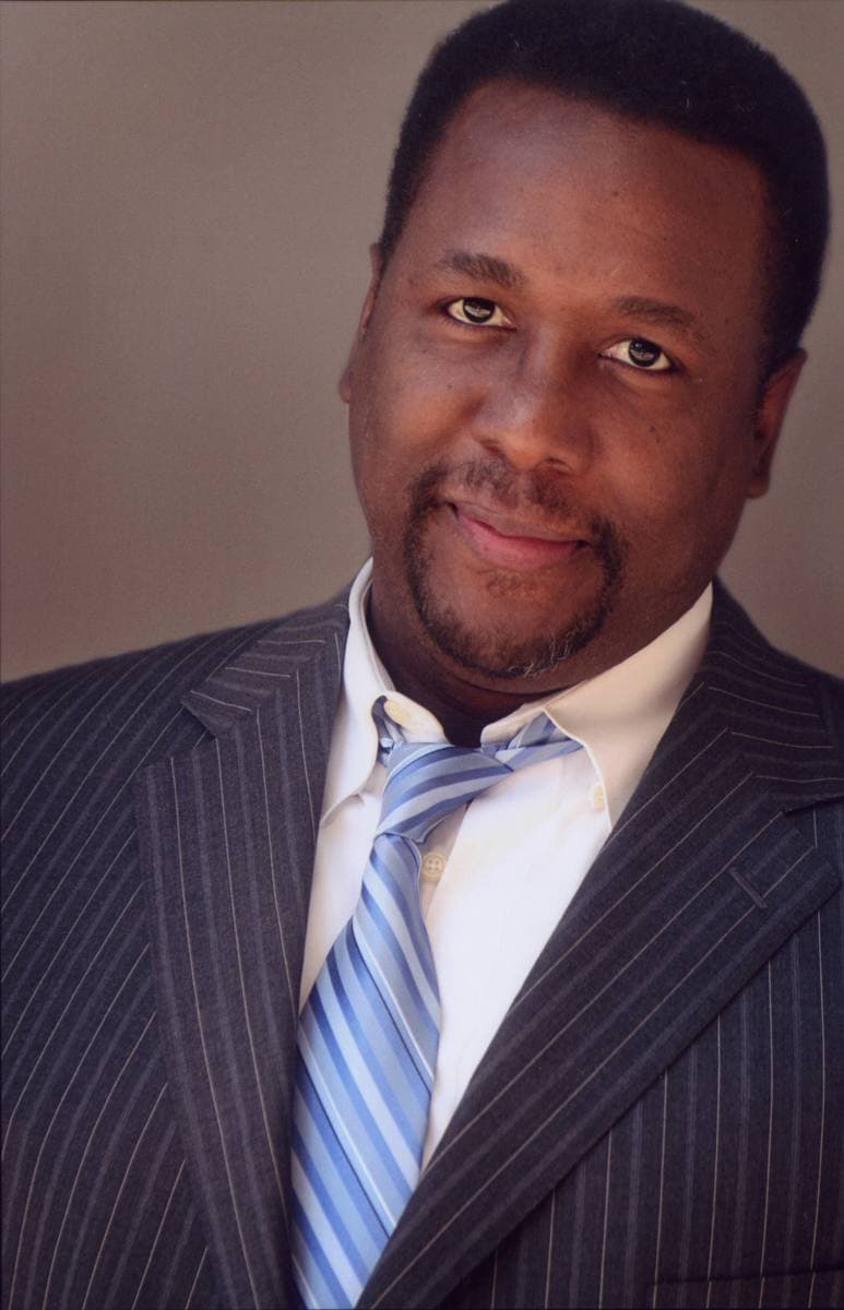 Wendell Pierce in a pinstripe suit and blue striped tie