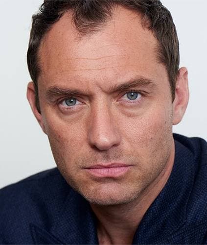 Jude Law in a dark jacket, looking straight at the camera