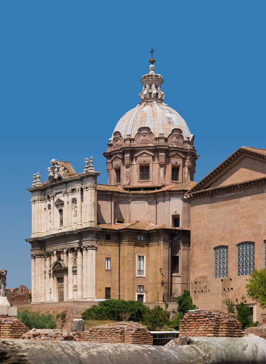 A baroque church with a ribbed dome above the brick ruins of the Forum