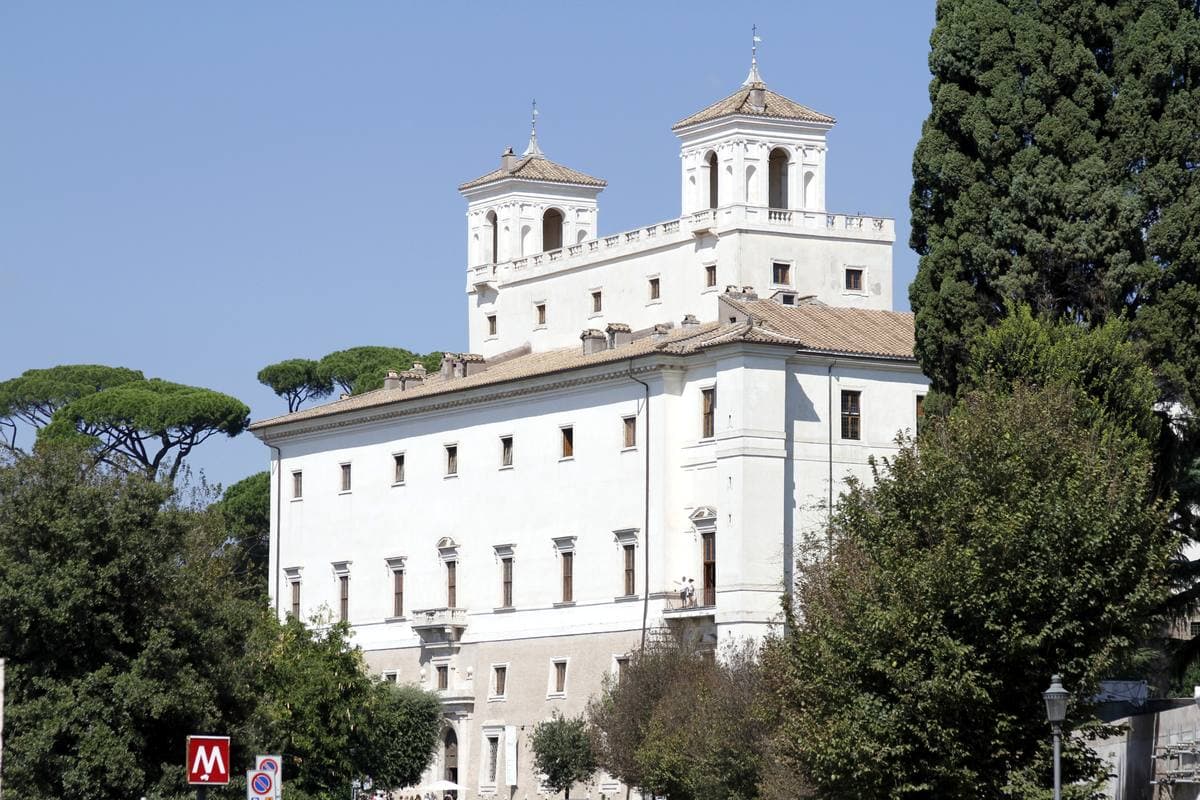 A white villa with two towers among umbrella pines