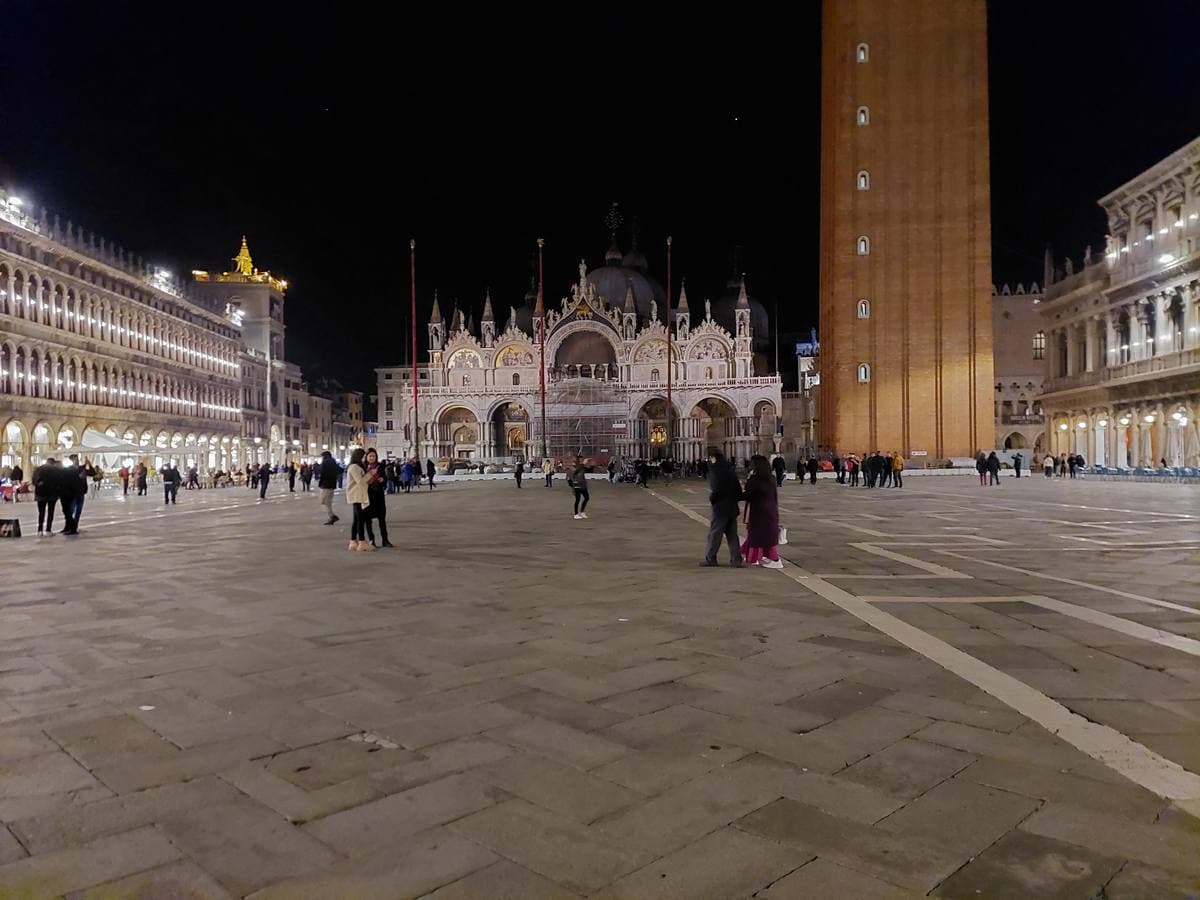 The floodlit front of St Mark’s Basilica across an almost empty square at night