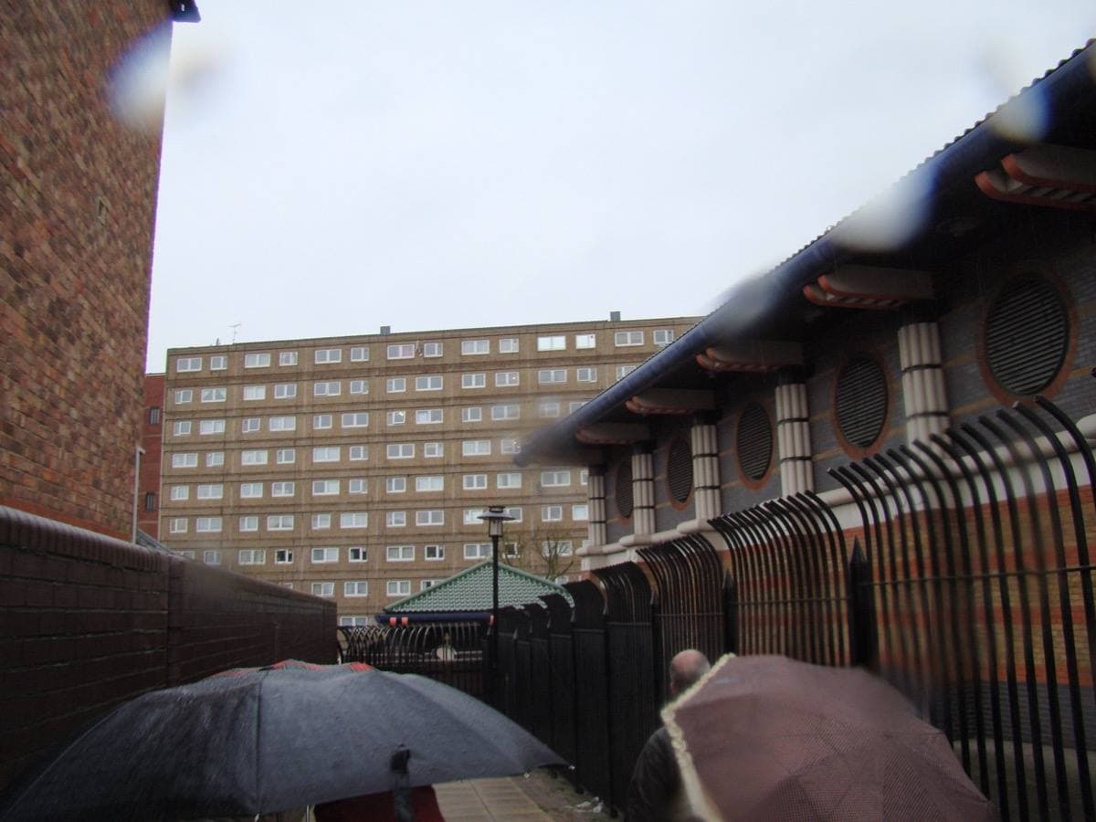 Low-rise and tower blocks of a 1960s housing estate seen along a narrow passage