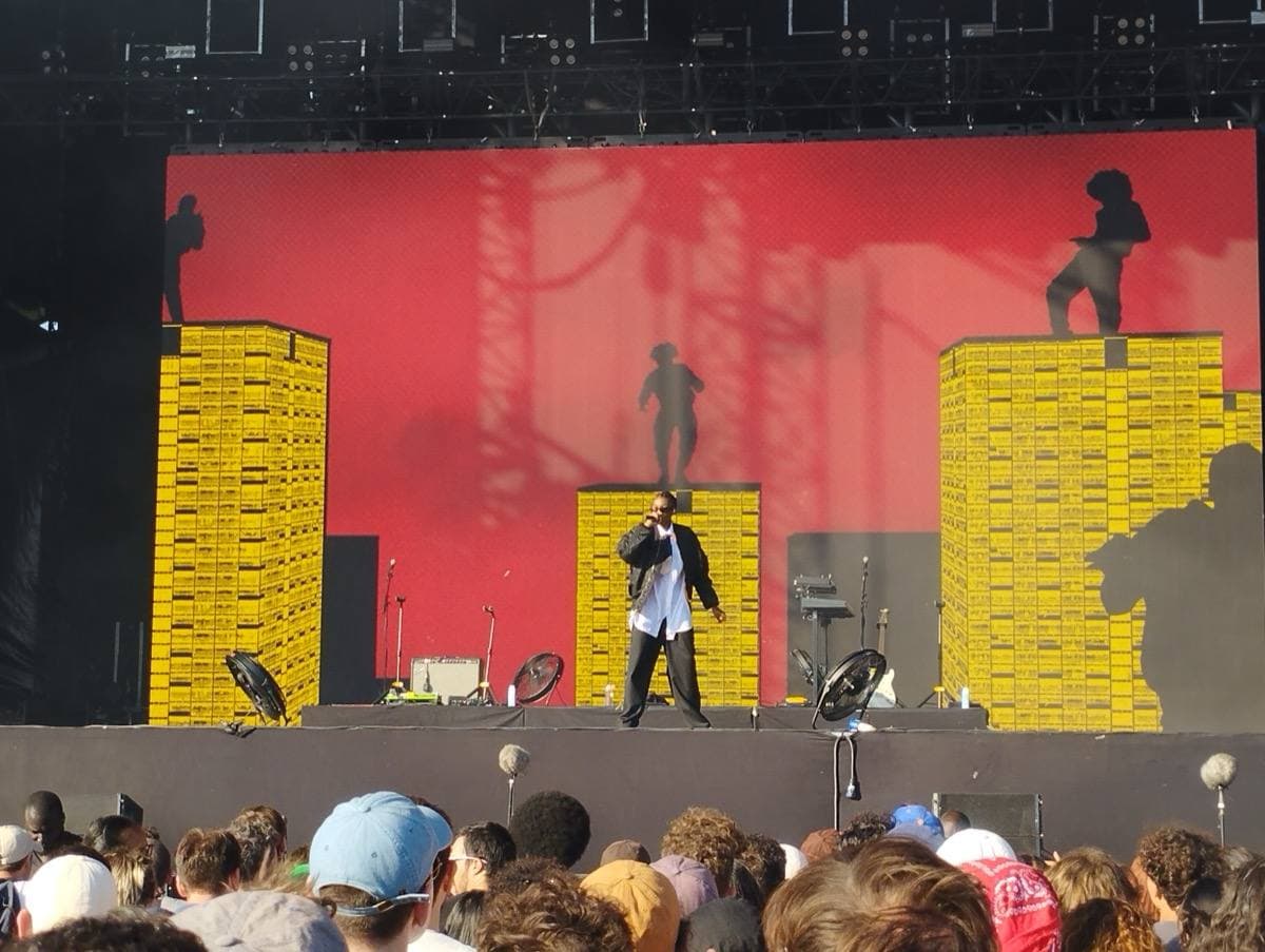 A performer on a festival stage under coloured lights